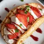 Single strawberry cheesecake taco filled with cream and berries