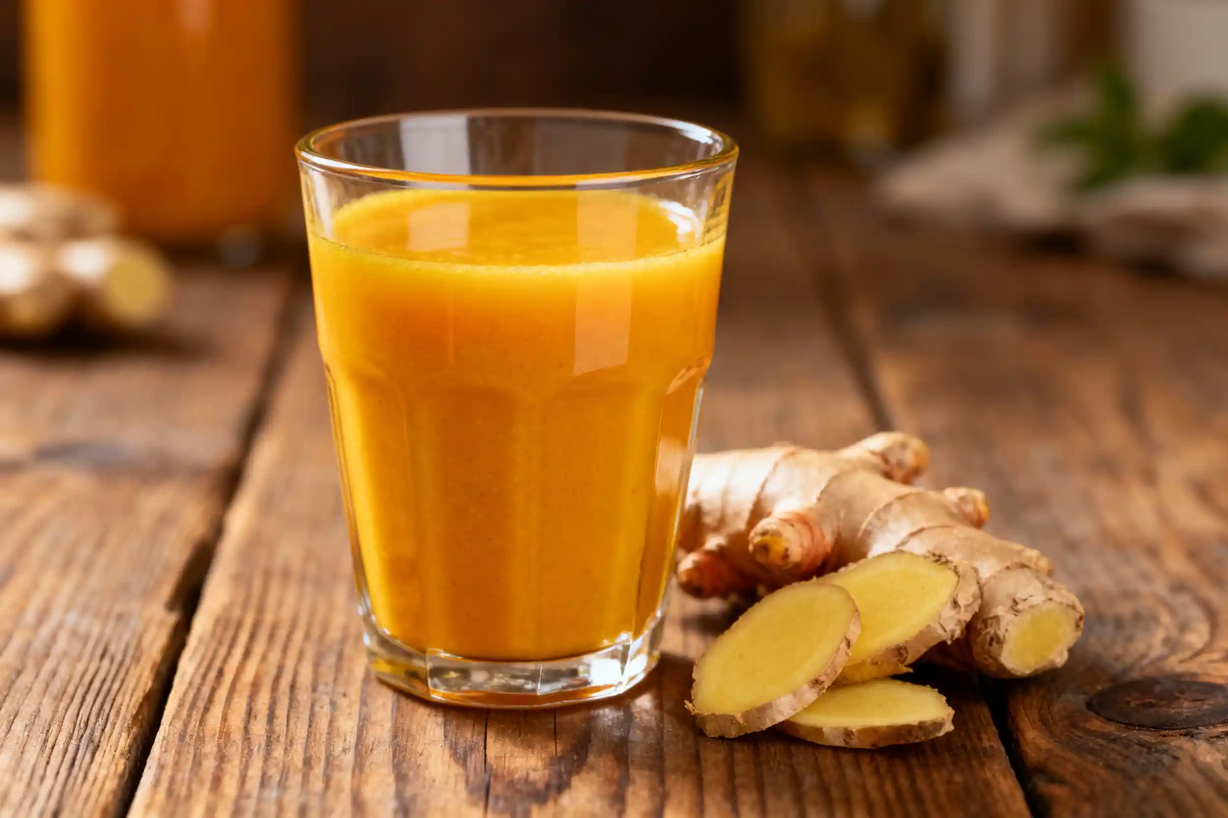 Fresh turmeric-ginger-shot with roots on rustic table