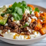 Cottage cheese beef bowl with seasoned ground beef, sweet potato and avocado on white ceramic bowl