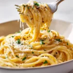 Ultimate Spaghetti Carbonara Recipe (Creamy, No Cream) 16 Plated ultimate spaghetti carbonara recipe in a white bowl with a fork twirling glossy pasta, extra Pecorino Romano grated on top.