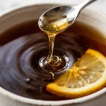 Classic black tea bag recipe in white mug with honey drizzle and lemon for recipe card