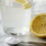 Dr oz baking soda trick morning routine glass with lemon and baking soda on white kitchen counter