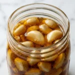 Dr William Li honey recipe fermented garlic cloves submerged in golden raw honey in a glass jar
