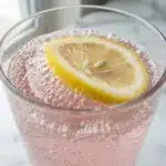 Finished what is the baking soda trick drink in tall clear glass with lemon slice and fine bubbles on white marble