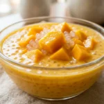 Close up mango sago recipe in a glass bowl with creamy mango base and tapioca pearls
