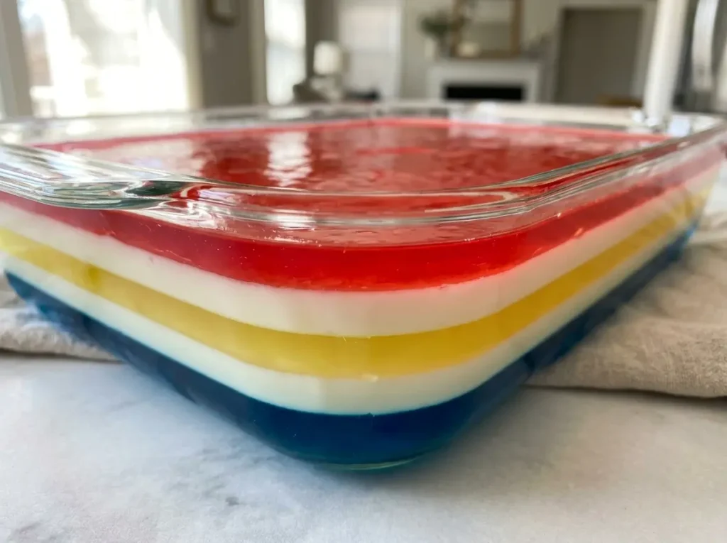 Layered Jello: 5 Easy Steps for Beautiful Rainbow Bars 10 Current image: Layered jello with red white yellow and blue stripes in a glass dish